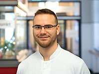 Junger Mann mit kurzen Haaren und Brille im Flur