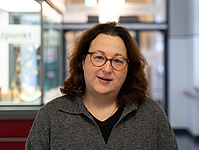Frau mit dunklen schulterlangen Haaren und Brille im Flur
